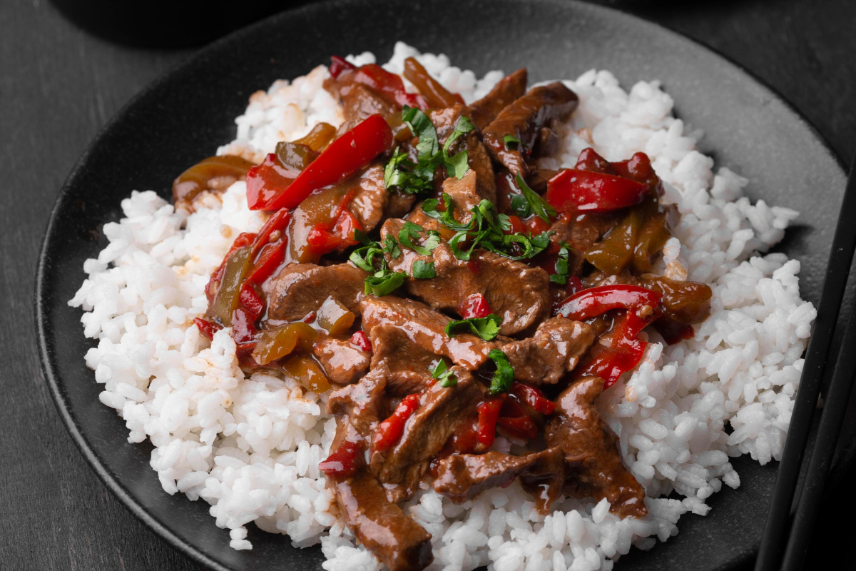 A mouthwatering dish of stir-fried beef and peppers served on a bed of fluffy white rice. 